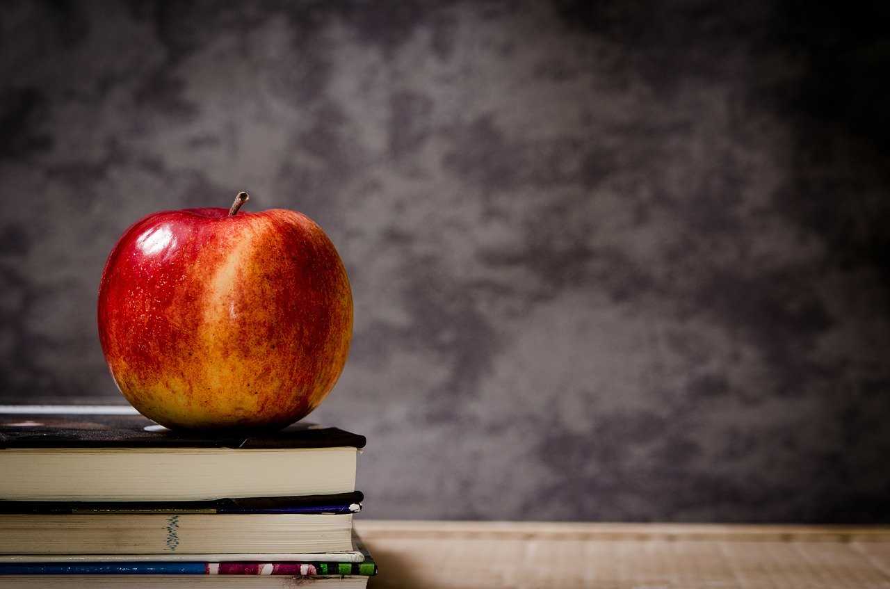 an apple is sitting on top of a pile of books