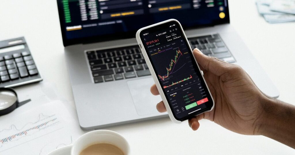 A hand holding a phone showing a stock investing app